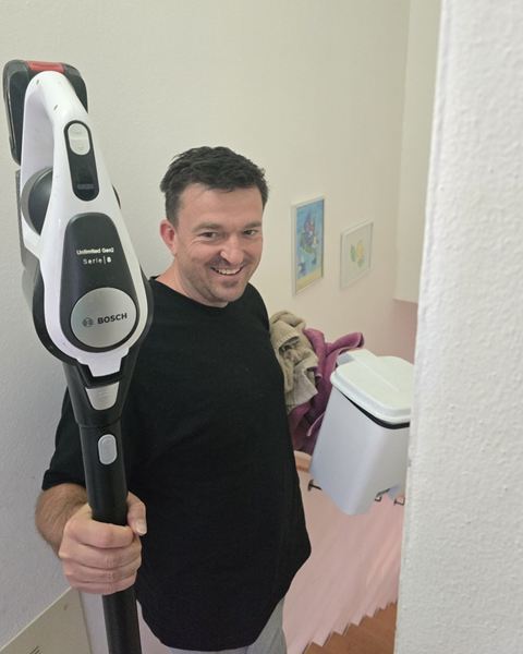 Florian lachend mit Staubsauger im Treppenhaus